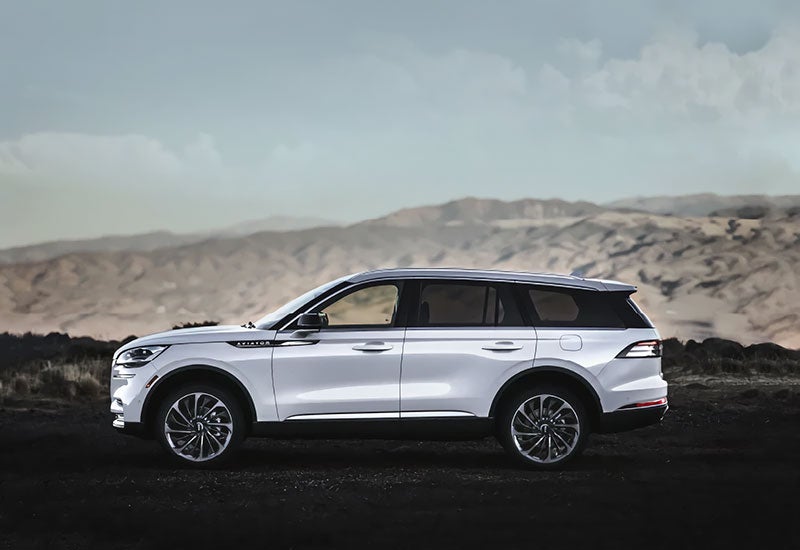 A 2022 Lincoln® Aviator in the Pristine White exterior color parked at a scenic mountain overlook