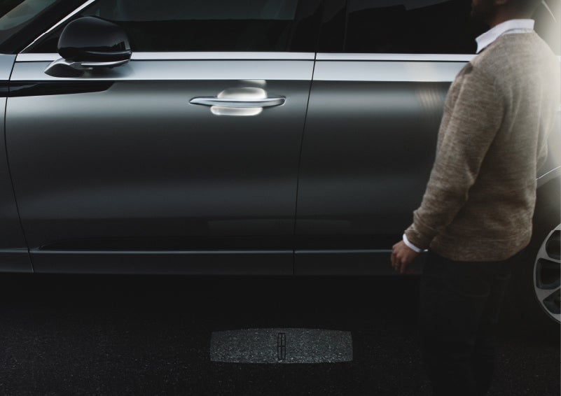 A person approaches a 2022 Lincoln® Aviator Grand Touring as the Lincoln® Embrace sequence of welcome lighting illuminates
