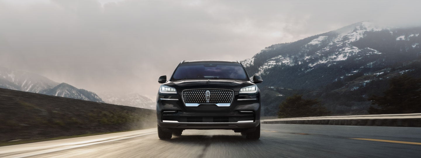 A 2022 Lincoln® Aviator is shown being driven along a road in a mountain valley