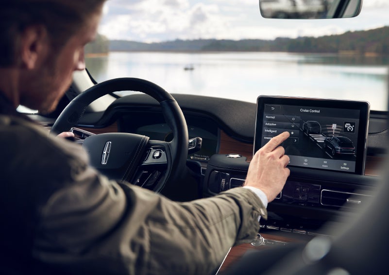 The driver of a 2022 Lincoln® Aviator adjusting the Available Intelligent Adaptive Cruise Control settings in the center touchscreen