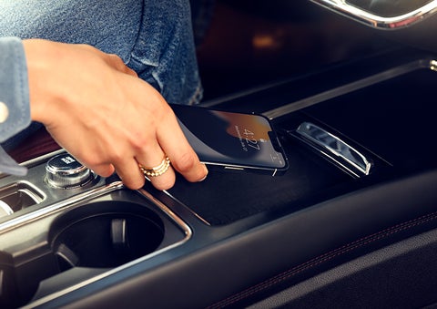 A hand is shown placing a smartphone on the available wireless charging pad. | Cavalier Lincoln in Chesapeake VA