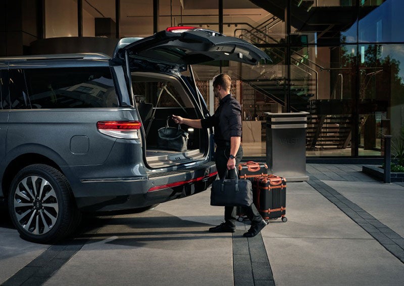 A valet is unloading luggage from the rear cargo area of a 2023 Lincoln Navigator SUV. | Cavalier Lincoln in Chesapeake VA