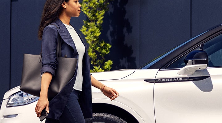 A woman approaches a 2024 Lincoln Corsair® SUV while holding a smartphone. | Cavalier Lincoln in Chesapeake VA