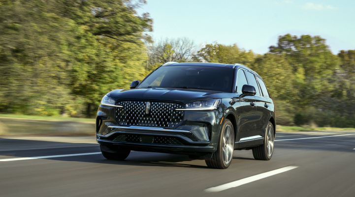 A 2025 Lincoln Black Label Aviator® SUV is being driven down a road lined with trees. | Cavalier Lincoln in Chesapeake VA