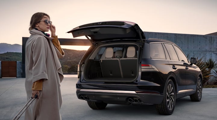 A woman approaches a 2026 Lincoln Aviator® SUV with its rear liftgate open. | Cavalier Lincoln in Chesapeake VA