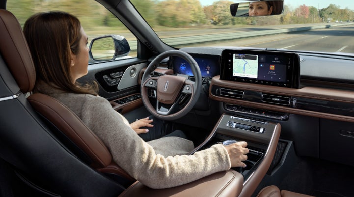 A 2027 Lincoln Aviator® SUV is being driven hands-free on a highway lined with trees. | Cavalier Lincoln in Chesapeake VA