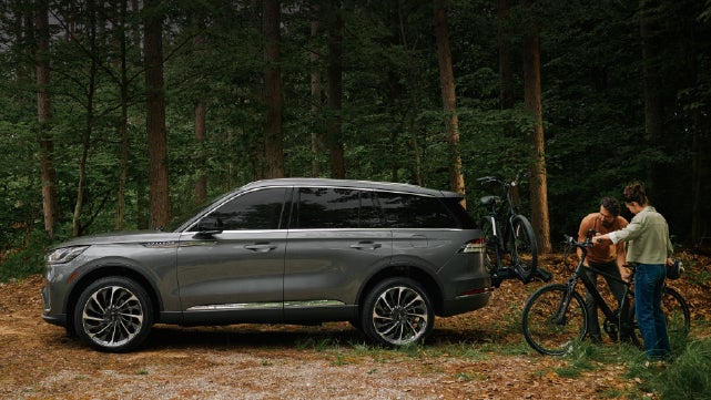 A father and son load e-bikes on a bike rack attached to a 2027 Lincoln Aviator® SUV. | Cavalier Lincoln in Chesapeake VA