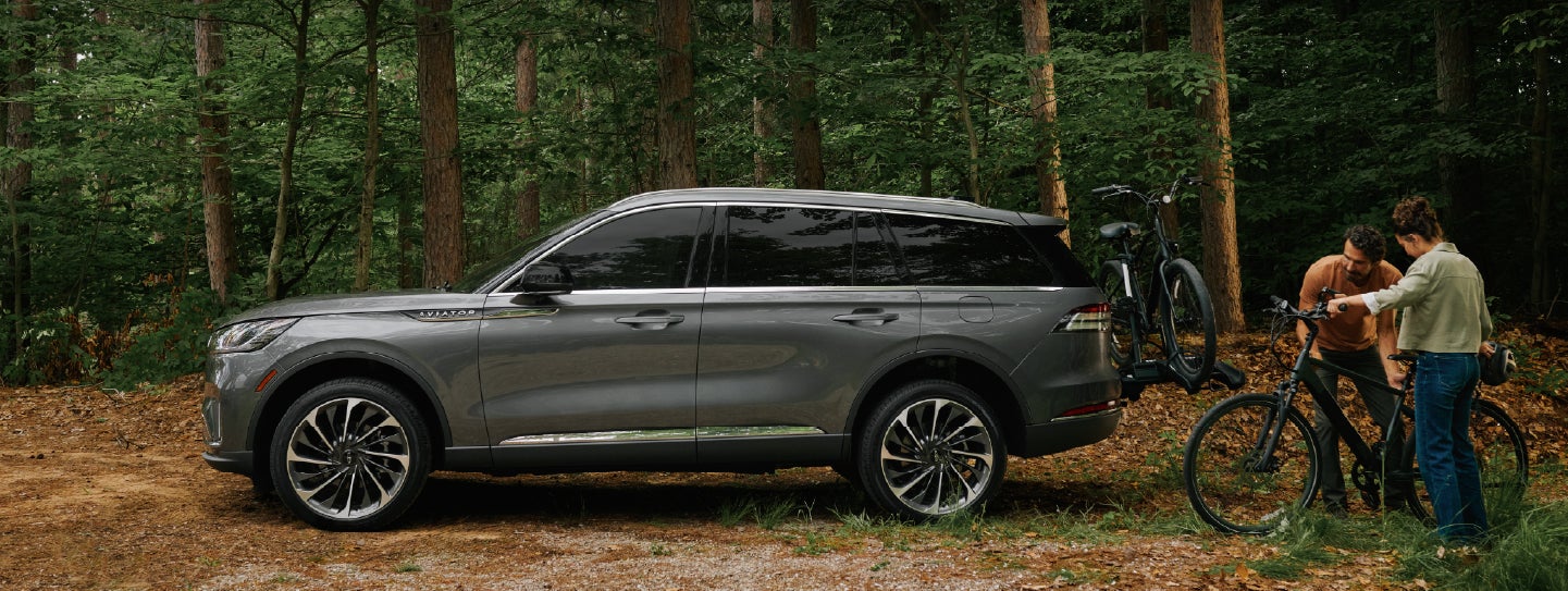 A father and son load e-bikes on a bike rack attached to a 2027 Lincoln Aviator® SUV. | Cavalier Lincoln in Chesapeake VA